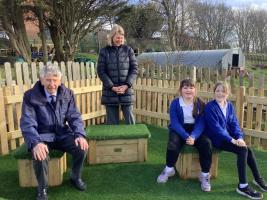 Jim Anderson putting one of the seats to good use at the opening of the new outdoor classroom and play area 